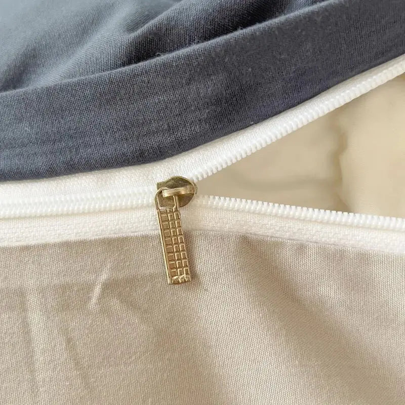 Gold-toned zipper pull with textured grid design on gray and beige solid color brush fabric duvet cover set by decorbites