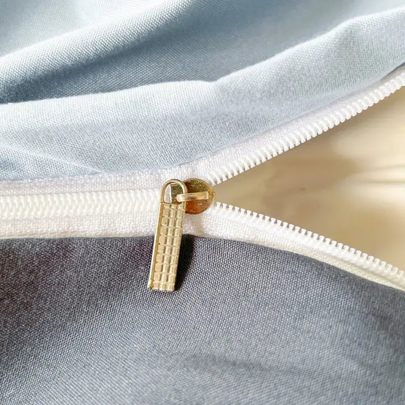 Gold-toned zipper pull with textured grid design on slider of solid color brush fabric duvet cover from decorbites bedding set