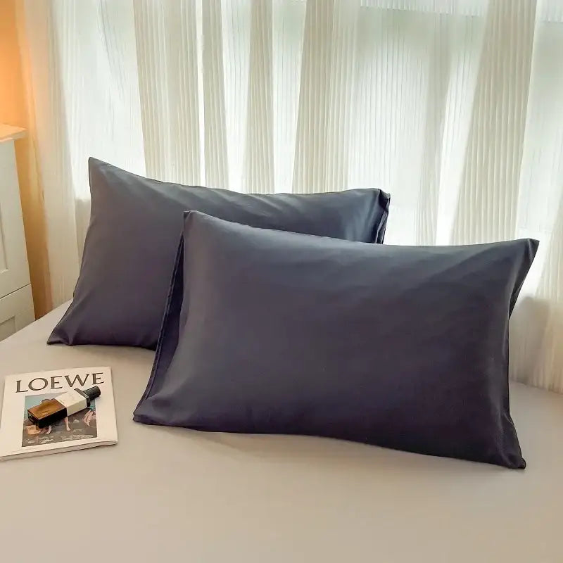 Two dark gray satin pillowcases from decorbites™ solid color brush fabric bedding set with duvet cover displayed on bed