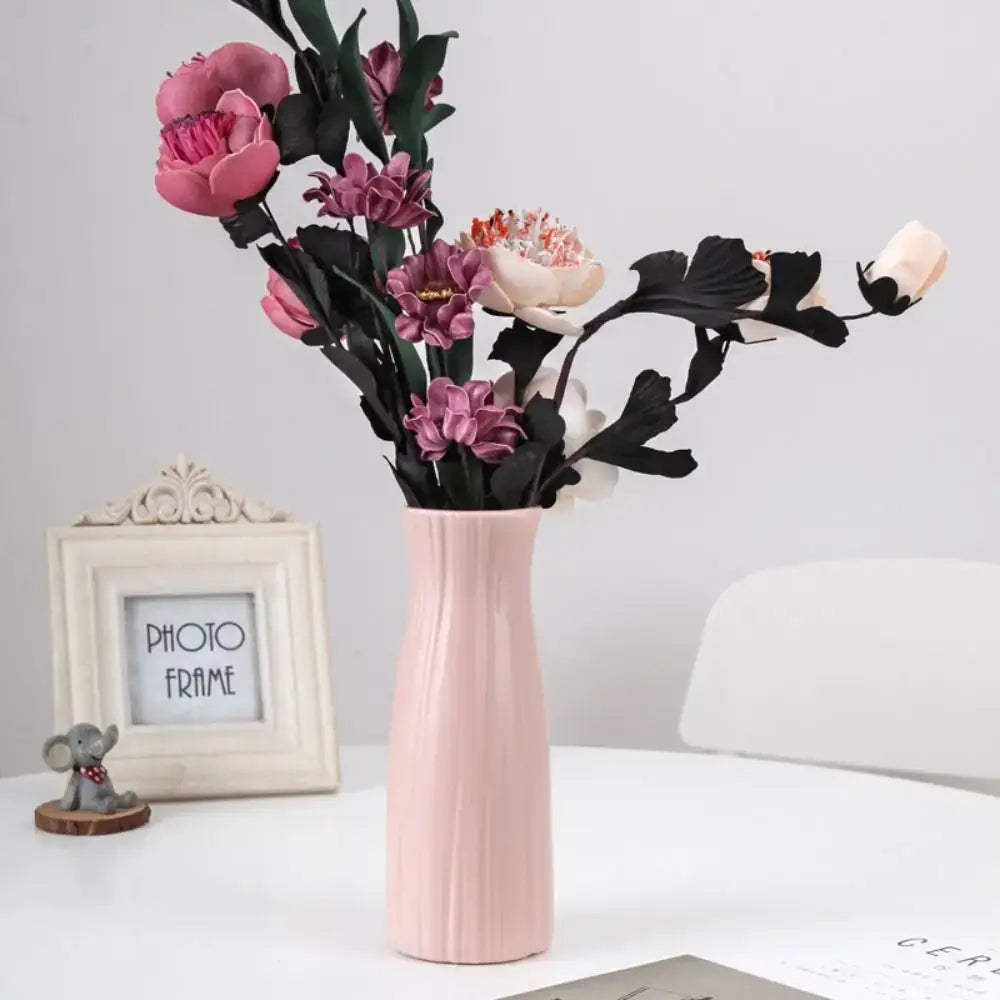 DecorBites solid color blush-pink plastic flower vase with vertical ridges holds pink and purple artificial flowers