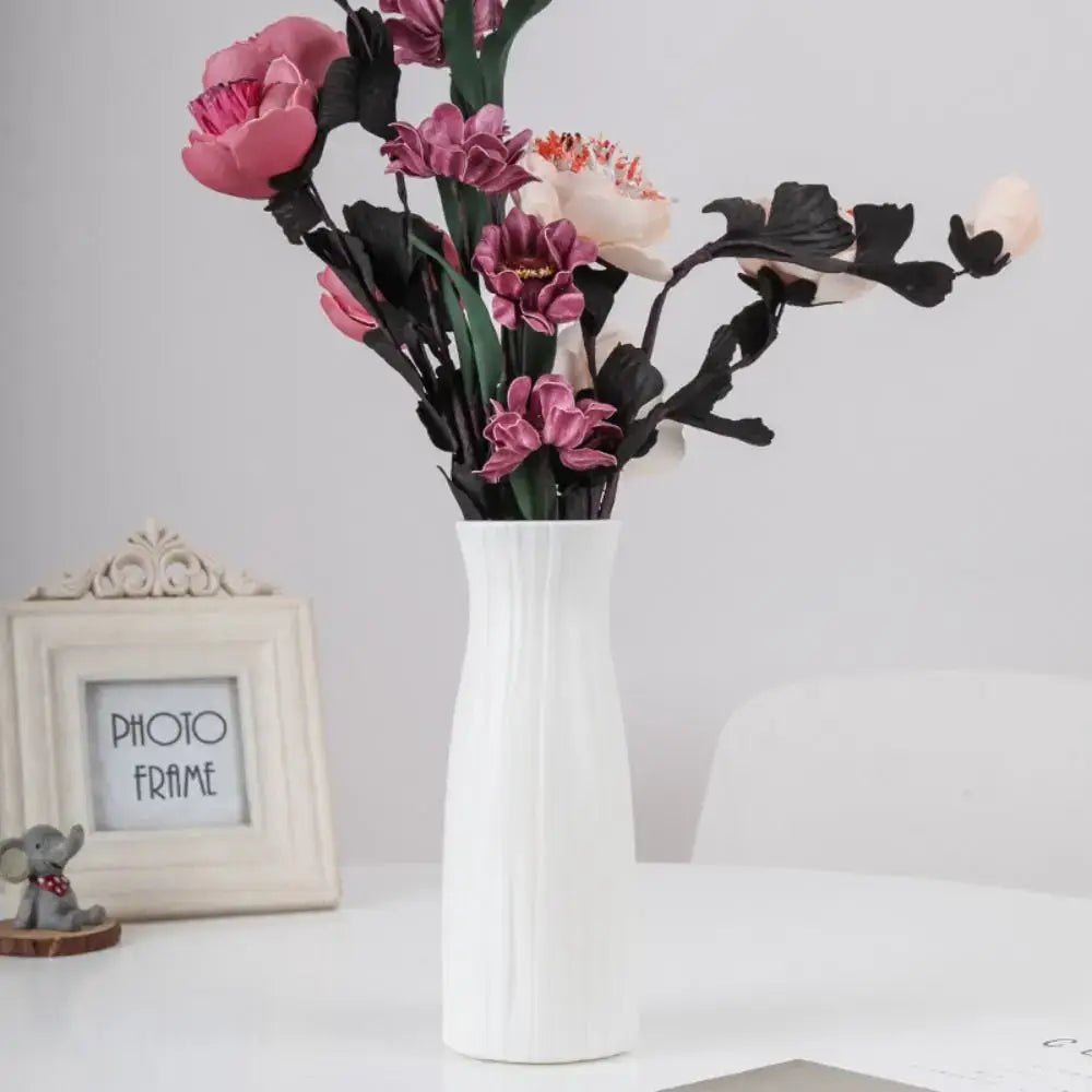 Weiße keramische einfarbig Plastikblumenvasen mit vertikalem geripptem Muster, die pinkfarbene, violette und cremefarbene künstliche Blumen hält