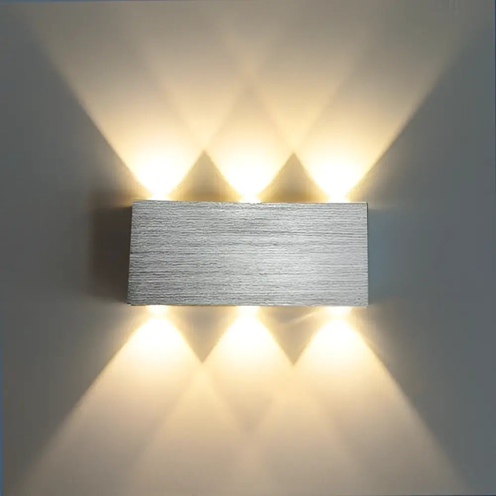 Silver rectangular decorbites sphera wall sconces with four warm LED lights casting geometric shadows
