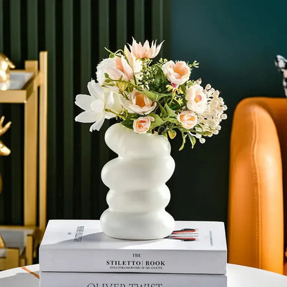 DecorBites spiral white vase made of ceramic with a wavy design holding pink and white artificial flowers