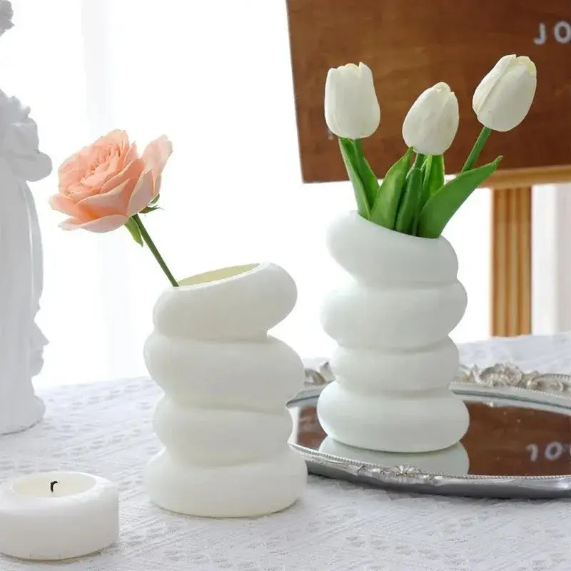 White ceramic spiral white vase with stacked rounded segments holding white tulips for home decoration