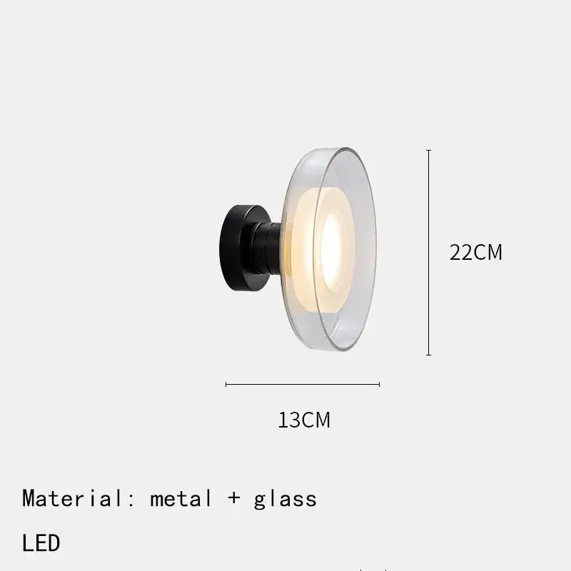 Modern minimalist DecorBites™ led wall lamp with sleek black metal base and transparent glass diffuser emitting warm light
