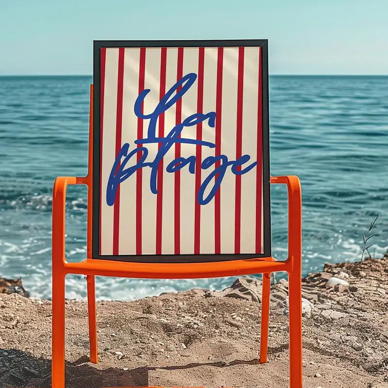 A framed decorbites summer vibe beach canvas art print with red and cream stripes and blue la plage script on orange chair