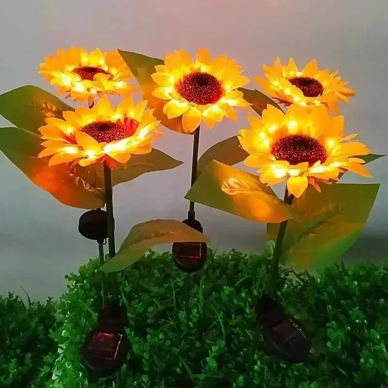 Five illuminated DecorBites™ sunflower solar garden lights with yellow petals and solar panels for solar lawn decor