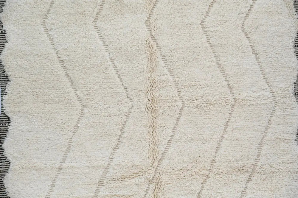 Cream-colored plush wool tapis beni ouarain with textured surface and subtle gray geometric zigzag patterns by DecorBites