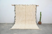 Cream-colored beni ouarain traditional tapis beni with textured handwoven surface and bold black zigzag fringed edges