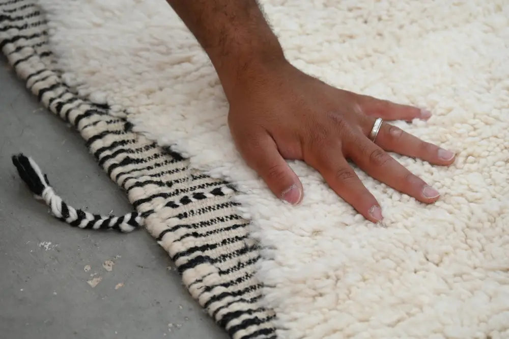 A plush white beni ouarain tapis beni with bold black and white striped fringe measuring 290 x 205 cm