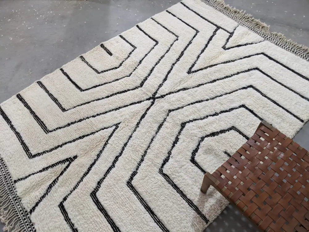 Cream-colored beni ouarain tapis with bold black geometric patterns and fringed edges by decorbites