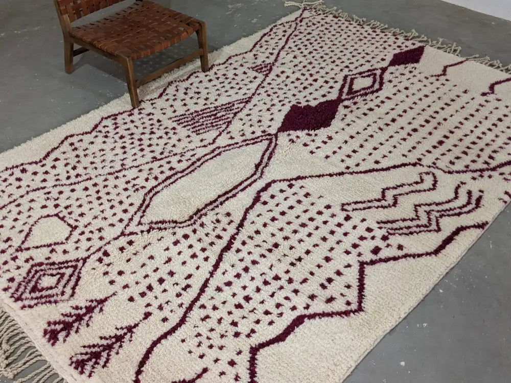 Cream-colored beni ouarain tapis beni with deep burgundy geometric patterns and fringed edges 307 x 213 cm