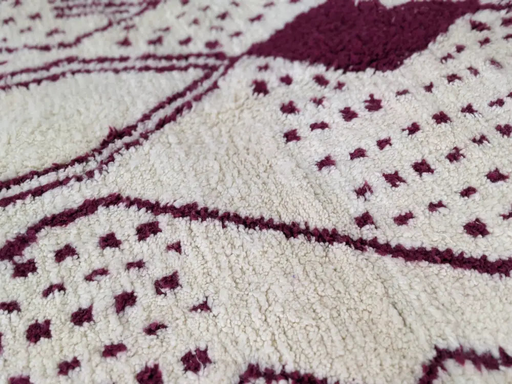 A plush cream-colored tapis beni ouarain with intricate maroon geometric patterns in a 307 x 213 cm size