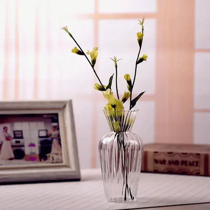 Clear glass transparent nordic vase with vertical ridges and fluted rim holding delicate yellow flowers by decorbites