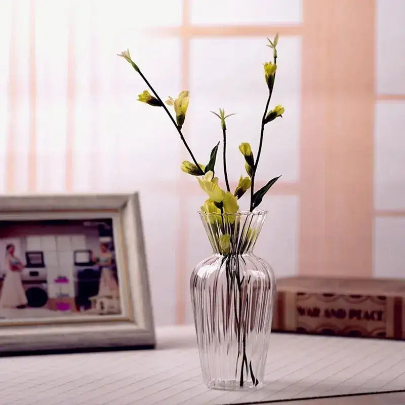 Clear glass transparent nordic vase with vertical ridges and fluted rim holding delicate yellow flowers by decorbites