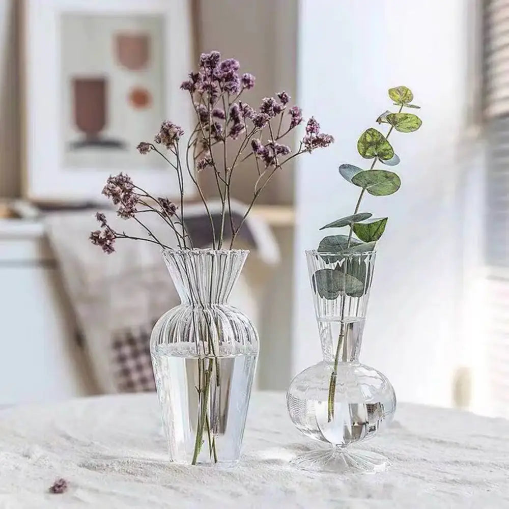 Two clear glass ribbed decorbites™ transparent nordic vases holding dried purple flowers and eucalyptus leaves