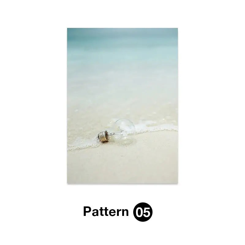 A clear glass incandescent bulb on wet sand by turquoise water featured in decorbites tropical ocean shell wall art