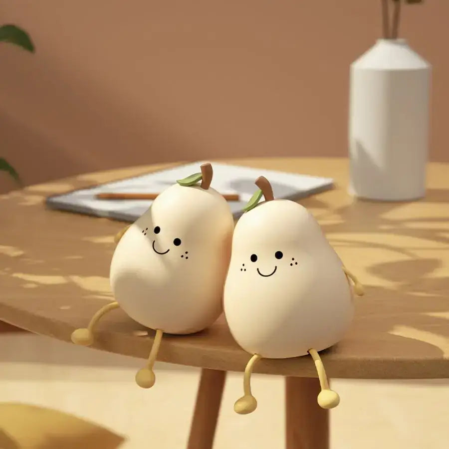 Two cream-colored silicone pear-shaped cartoon night lights with rechargeable battery and touch sensor on wooden table
