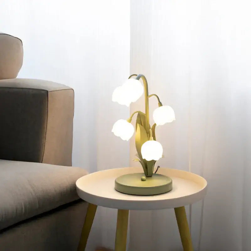 Delicate gold-toned vintage floral table lamp shaped like white lily flowers with green leaves on a circular base