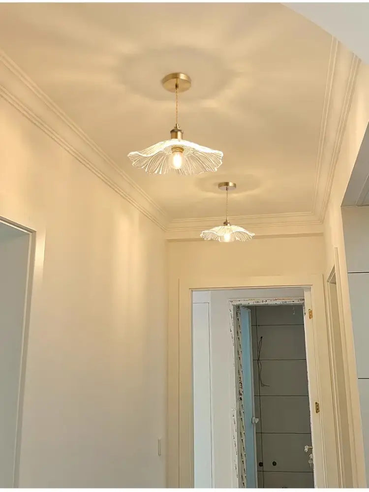 Two elegant brass-finished pendant lights with translucent flower glass shades for stylish home decor by DecorBites™