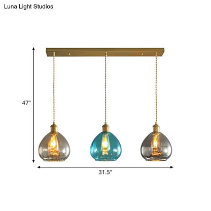 Three pendant glass onion multi ceiling lights with brass fixtures and teal tan smoky gray glass shades on gold bar