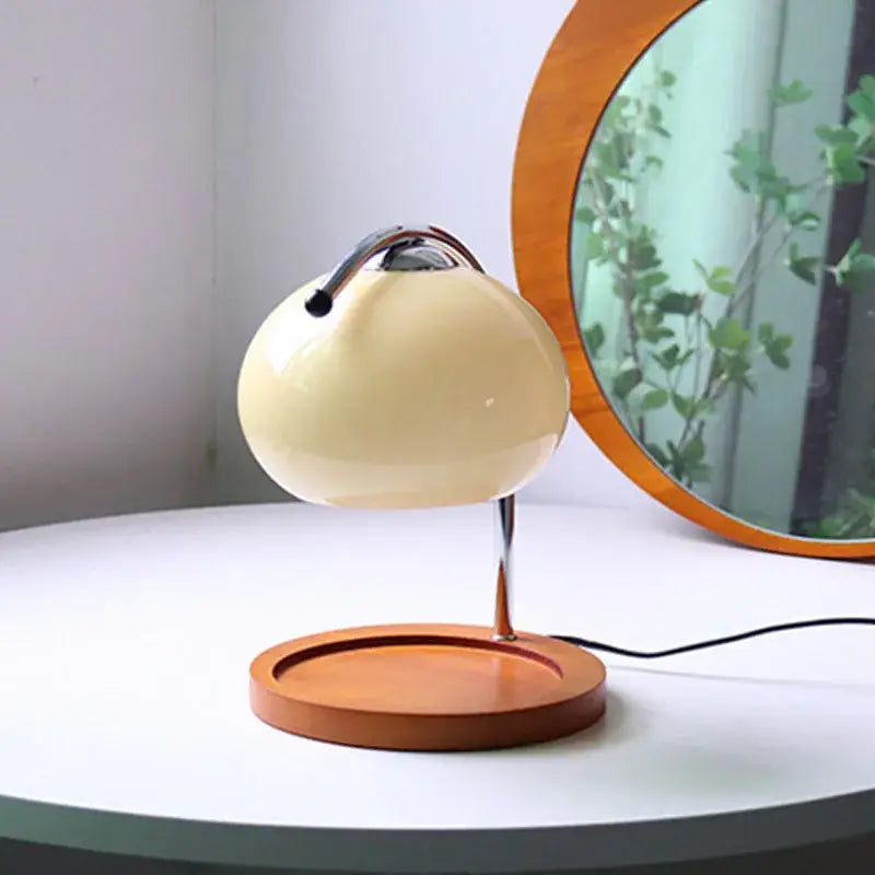 Cream-colored glossy ceramic table lamp with curved chrome handle on wooden base for vintage glass table decor