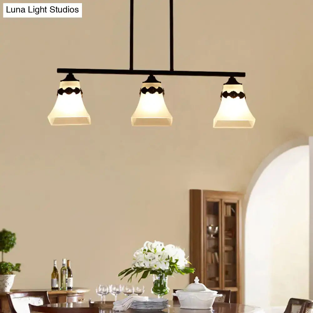 Black metal pendant light fixture with three off-white handblown glass shades and decorative bird accent for kitchen island