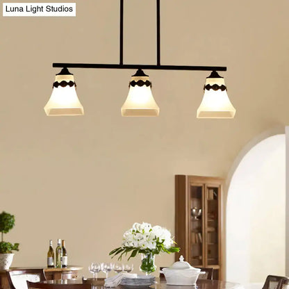 Black metal pendant light fixture with three off-white handblown glass shades and decorative bird accent for kitchen island