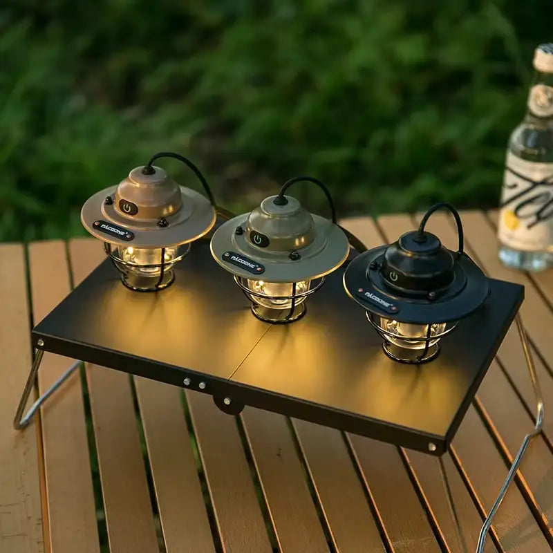 Three illuminated decorbites™ vintage outdoor rechargeable camping chandelier lights with metal cages and typec rechargeable power buttons on a table