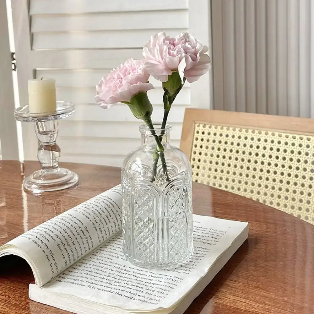 Clear glass vintage relief vase with intricate etched patterns holding two light pink carnations for hydroponic plants