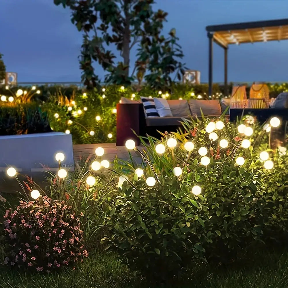 String of DecorBites™ warm white solar led firework lights with spherical bulbs on slender stems among green foliage
