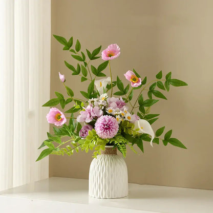 A white ripple plastic vase by decorbites with ribbed texture and rope band holding pink peonies and green foliage