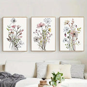 Three framed watercolor flower posters with delicate pink white and green blooms on cream canvas for wall decor