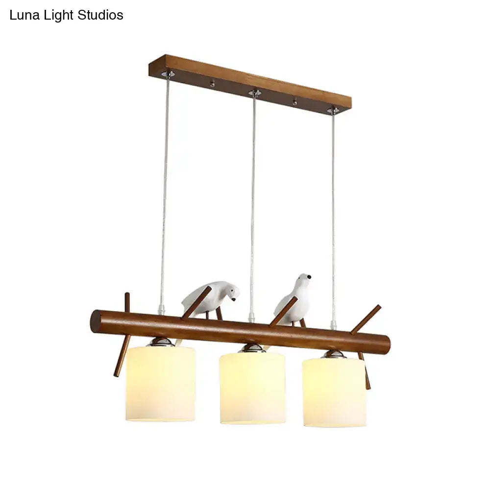 Decorbites™ white glass led pendant light with resin bird featuring three warm cylinder restaurant shades on wood bar