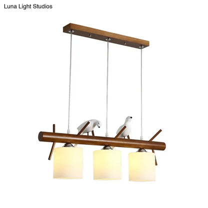 Decorbites™ white glass led pendant light with resin bird featuring three warm cylinder restaurant shades on wood bar
