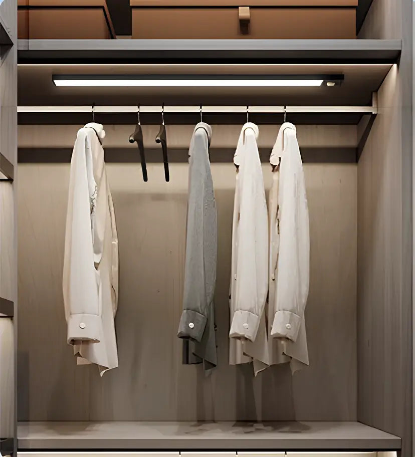 Decorbites™ wireless under cabinet lighting illuminating a sleek minimalist closet with white and gray dress shirts