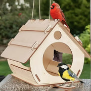 A light-colored wooden bird feeder with a slanted roof and circular entrance featuring two birds perched on it