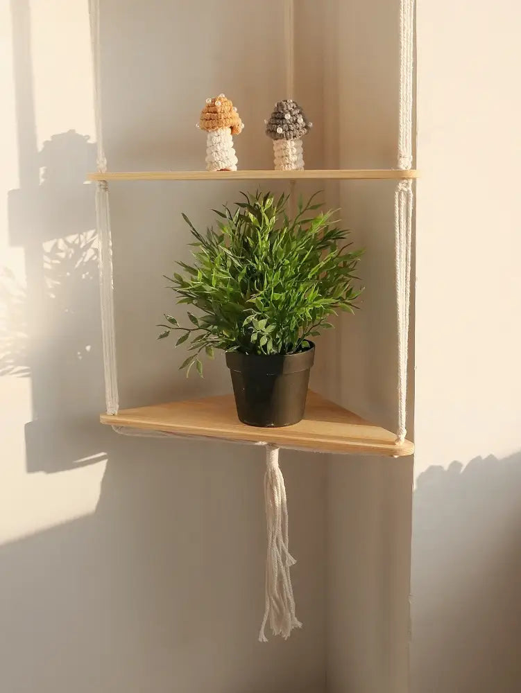 Decorbites™ wooden corner shelf with light wood slats and white macrame holding a potted plant in a black pot