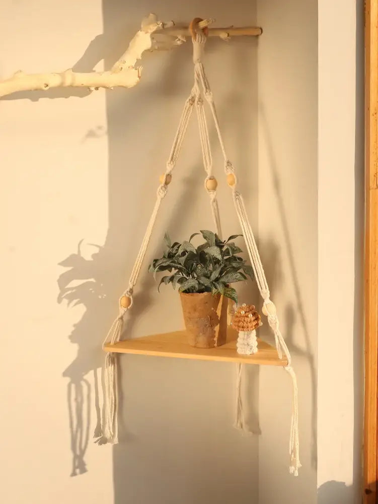 Beige decorbites wooden corner shelf with macrame hanging design wooden beads tassels holding potted plant