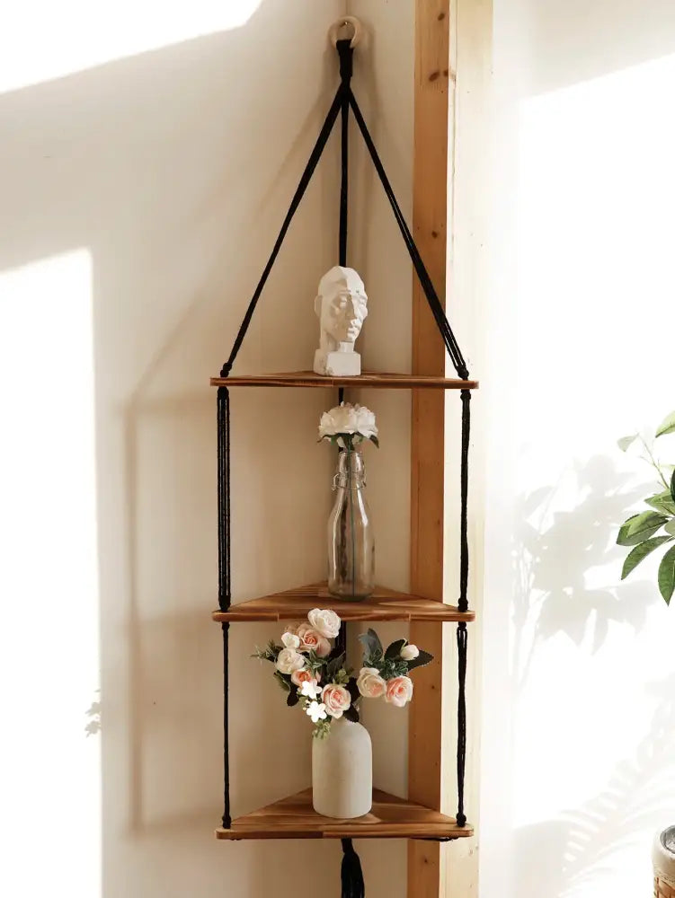 Black macrame cord suspends three wooden triangular shelves in a boho wooden corner shelf by DecorBites wooden corner shelf