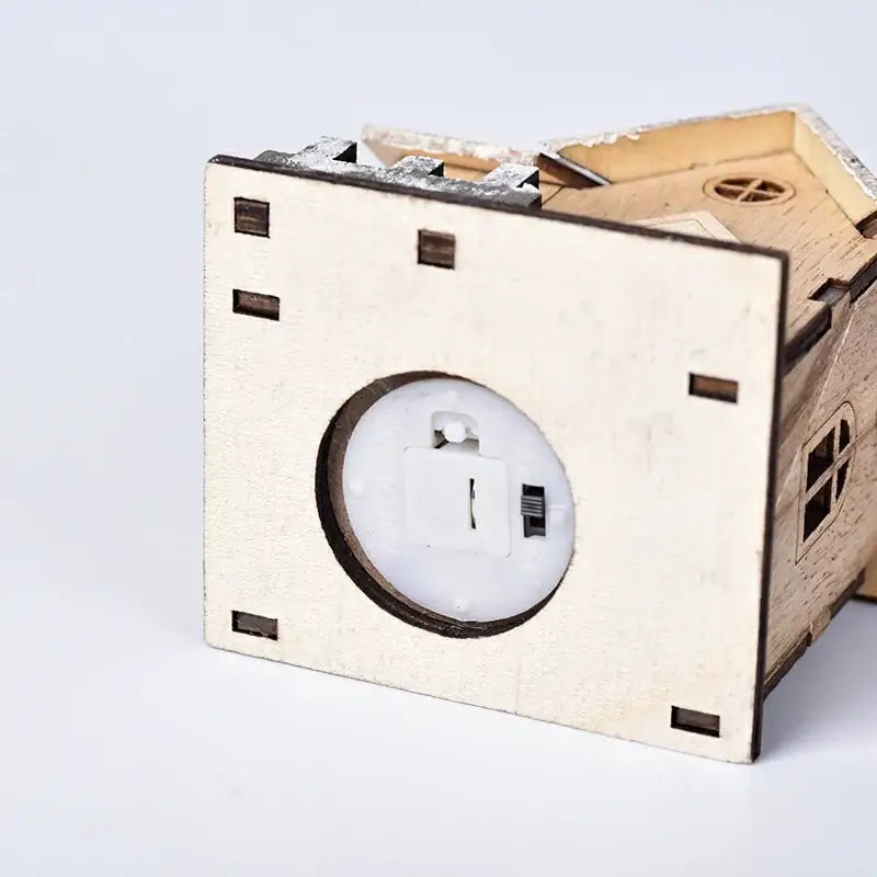 A light-up wooden led light house piggy bank by decorbites with small windows and a battery compartment visible
