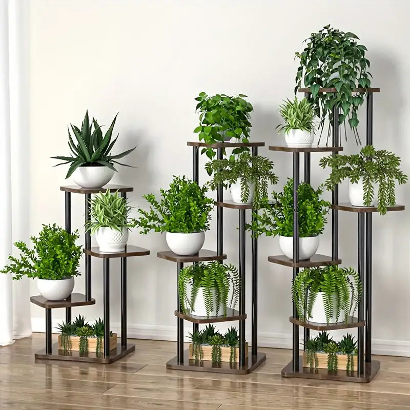 Set of three tiered decorbites wooden plant stands with dark brown shelves and black metal frames holding green plants