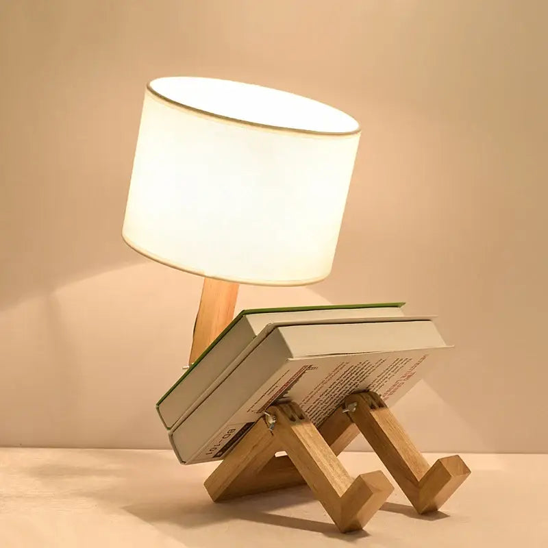 Minimalist decorbites™ wooden robot shape creative table lamp with white fabric shade on stacked books v shaped stand