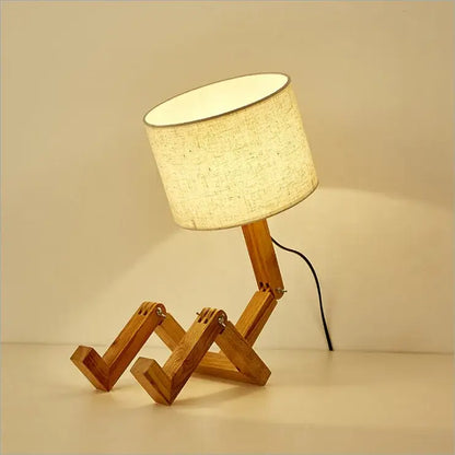 Wooden robot shape table lamp with beige fabric shade and articulated wooden legs for indoor study and reading