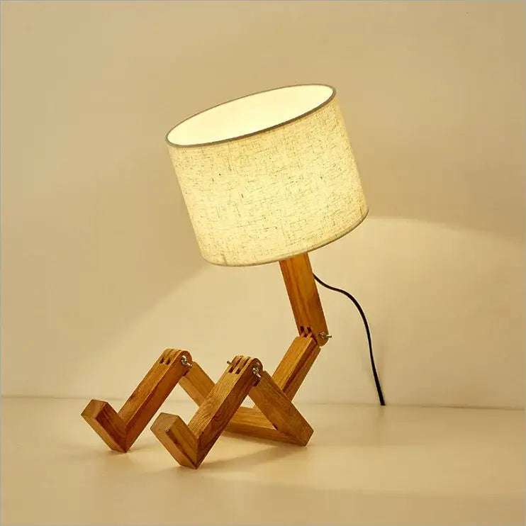 Wooden robot shape table lamp with beige fabric shade and articulated wooden legs for indoor study and reading
