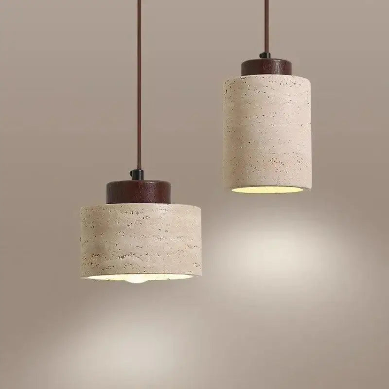 Two cylindrical concrete led pendant lights with dark wood accents and warm illumination in a stone chandelier design