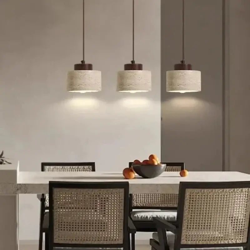 Three decorbites™ yellow stone led pendant chandeliers with off-white textured shades and dark metal fixtures above table