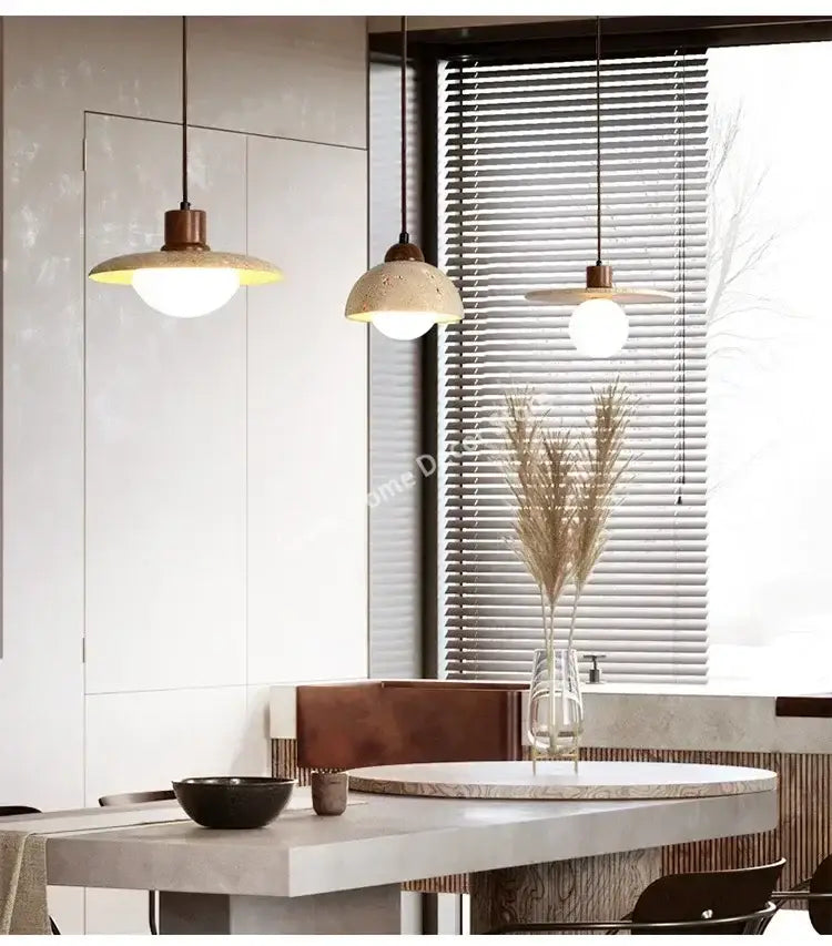 Decorbites™ yellow travertine pendant light features warm-toned stone pendant shades with copper fixtures above dining table