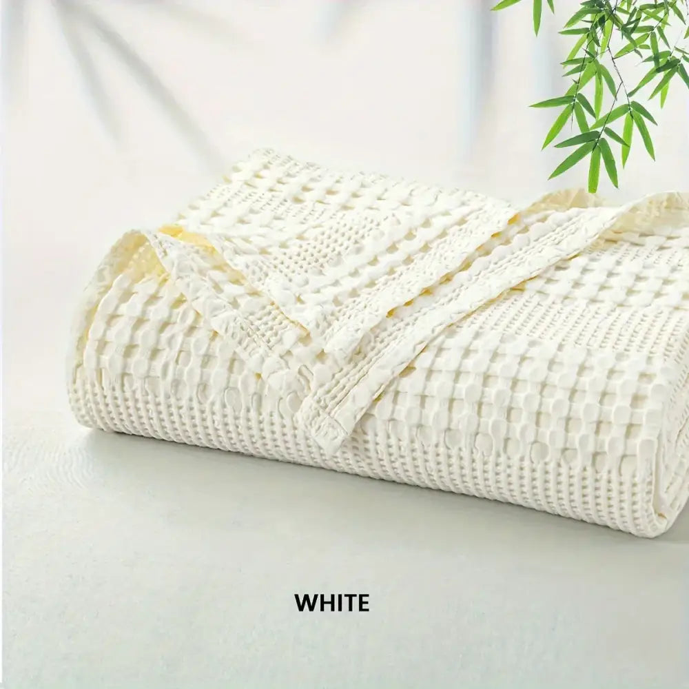A white bamboo cotton waffle blanket with soft textured surface and neatly folded edges by decorbites bamboo cotton