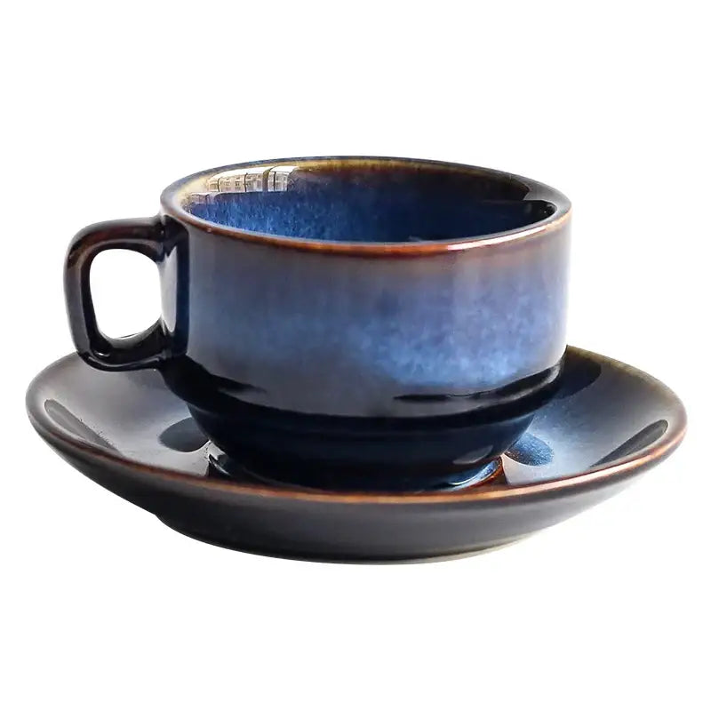 A deep blue glossy ceramic espresso coffee cup with brown rim on matching coffee cup saucer set for dining room